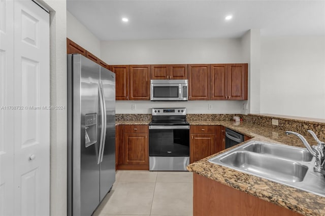 kitchen with appliances with stainless steel finishes, light tile patterned floors, dark stone counters, and sink