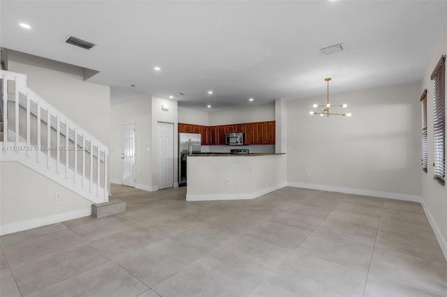 kitchen featuring kitchen peninsula, an inviting chandelier, decorative light fixtures, and appliances with stainless steel finishes