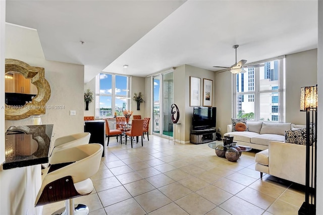 living room with ceiling fan, a healthy amount of sunlight, light tile patterned floors, and expansive windows