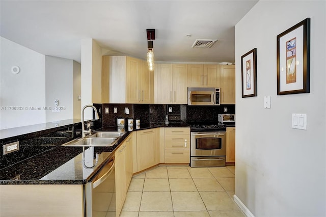 kitchen featuring light brown cabinetry, sink, dark stone countertops, stainless steel appliances, and decorative backsplash