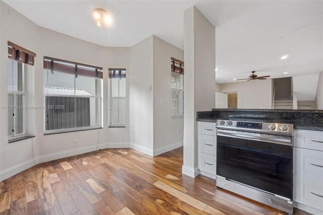 kitchen with ceiling fan, stainless steel electric range oven, light hardwood / wood-style floors, and white cabinets