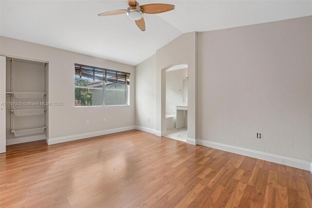 unfurnished bedroom featuring lofted ceiling, connected bathroom, ceiling fan, and light hardwood / wood-style flooring