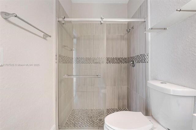 bathroom featuring a shower with door and toilet