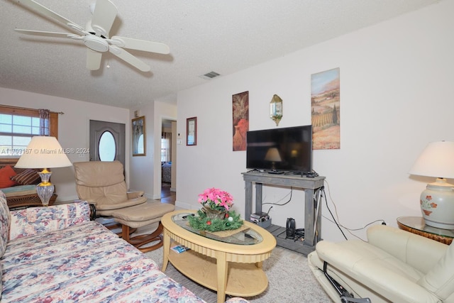 living room featuring ceiling fan and a textured ceiling