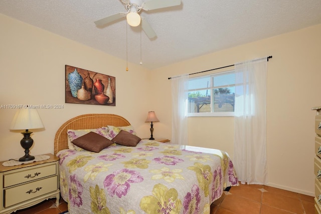 bedroom with a textured ceiling, tile patterned floors, and ceiling fan