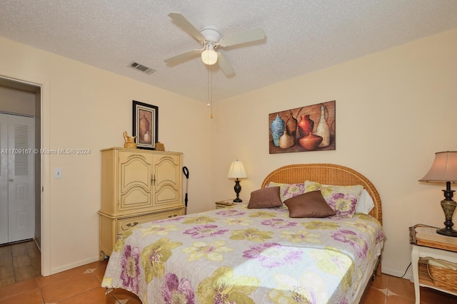 tiled bedroom featuring ceiling fan and a textured ceiling