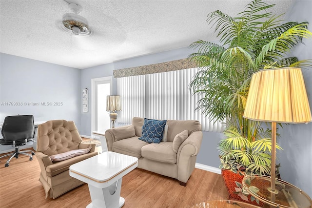 living room with a textured ceiling, ceiling fan, and light wood-type flooring