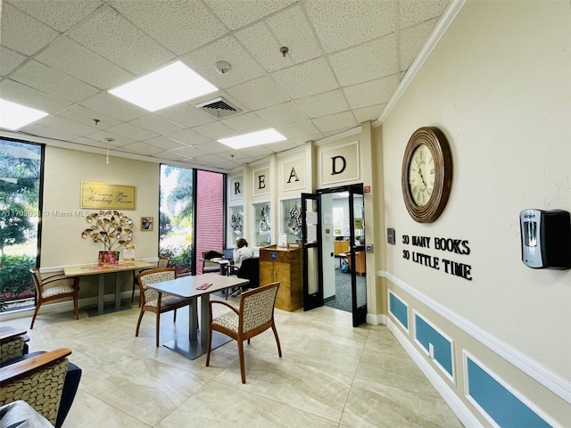 interior space with a paneled ceiling, ornamental molding, and expansive windows