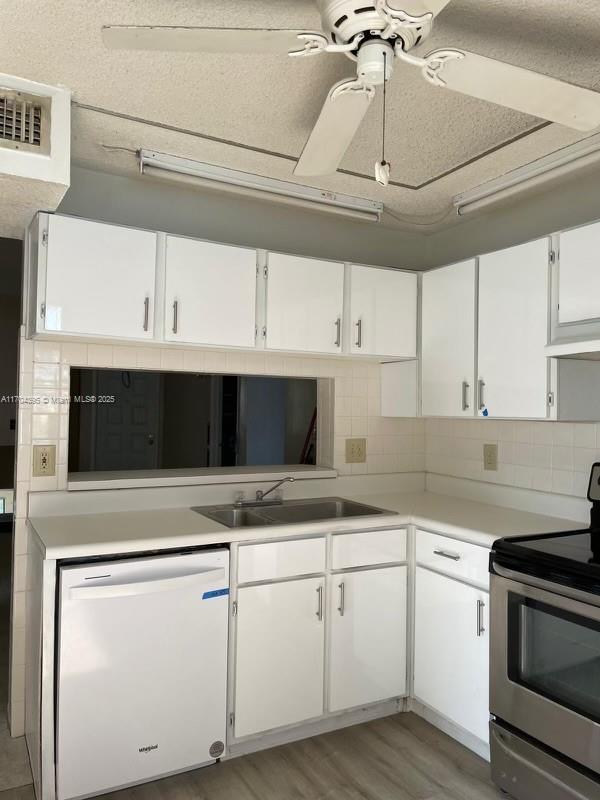 kitchen featuring stainless steel range with electric cooktop, white cabinetry, tasteful backsplash, sink, and white dishwasher