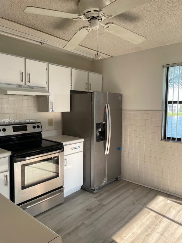 kitchen featuring appliances with stainless steel finishes, a textured ceiling, white cabinets, light hardwood / wood-style flooring, and ceiling fan