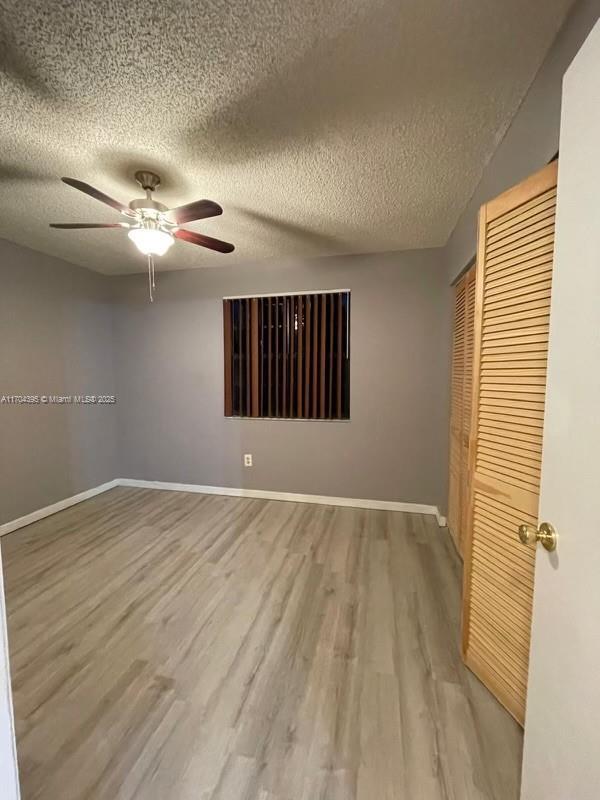 unfurnished bedroom featuring hardwood / wood-style floors, a textured ceiling, a closet, and ceiling fan