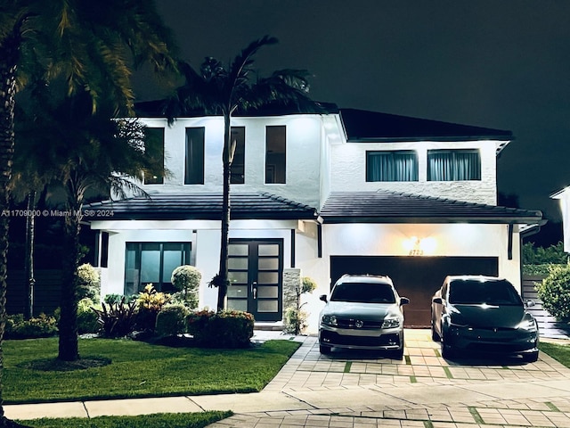 view of front of property featuring a garage, french doors, and a front lawn