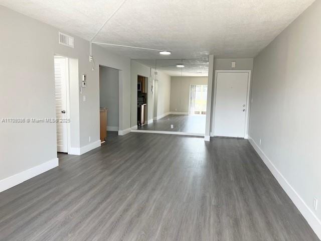 empty room featuring a textured ceiling and dark wood-type flooring