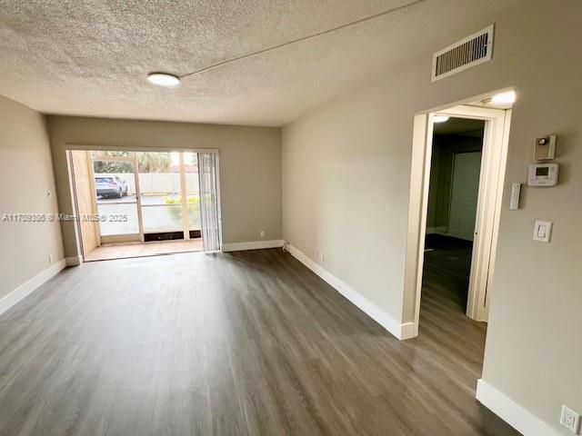 empty room featuring a textured ceiling and dark wood-type flooring