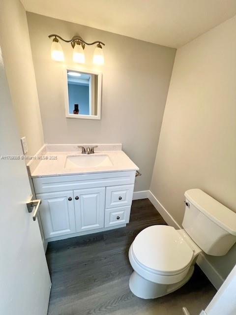 bathroom featuring toilet, vanity, and hardwood / wood-style flooring