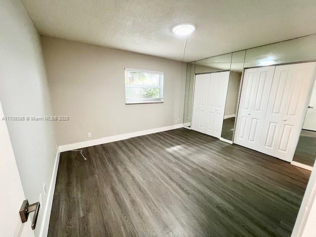 unfurnished bedroom with dark hardwood / wood-style flooring and a textured ceiling