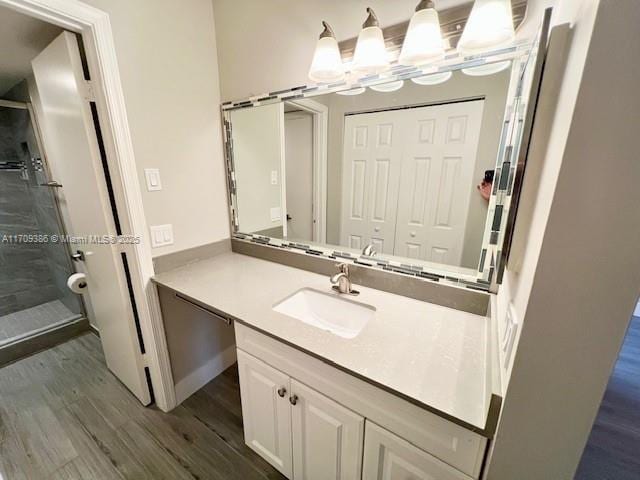 bathroom with hardwood / wood-style floors, vanity, and an enclosed shower