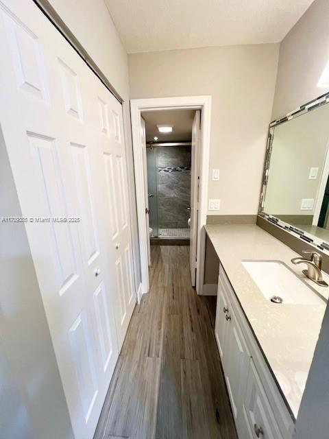 bathroom with hardwood / wood-style floors, vanity, and tiled shower