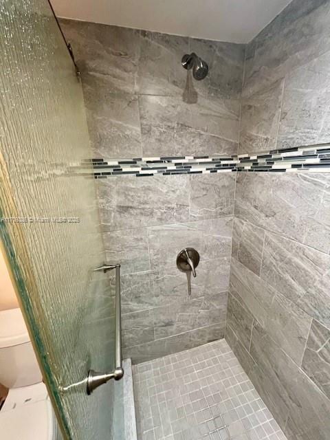 bathroom with a shower with door and toilet