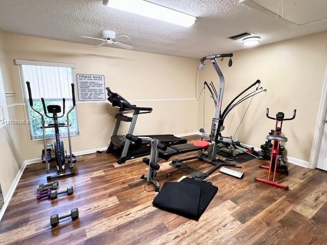 workout room with hardwood / wood-style flooring, ceiling fan, and a textured ceiling