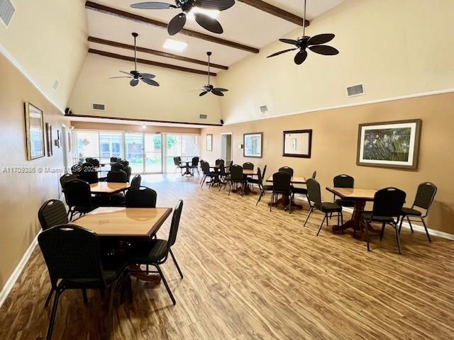 dining room featuring beamed ceiling, hardwood / wood-style floors, and high vaulted ceiling