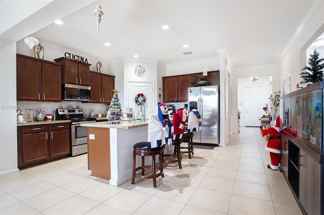 kitchen featuring stainless steel appliances, tasteful backsplash, light stone counters, a kitchen island with sink, and ornamental molding