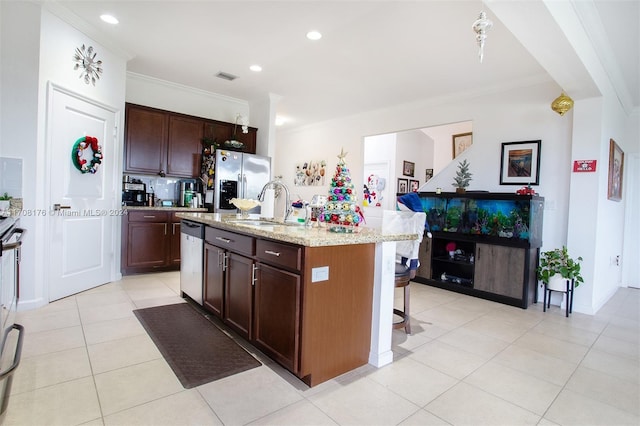 kitchen featuring dark brown cabinetry, stainless steel appliances, crown molding, a kitchen island with sink, and light tile patterned flooring