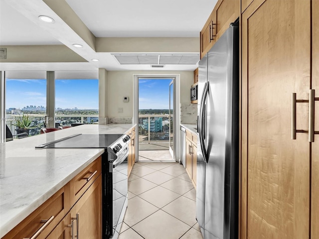 kitchen with light stone countertops, light tile patterned flooring, and stainless steel appliances