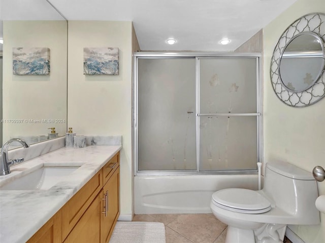 full bathroom with toilet, vanity, tile patterned floors, and bath / shower combo with glass door