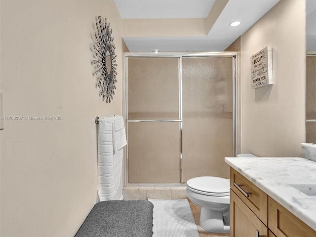 bathroom featuring tile patterned floors, vanity, toilet, and a shower with shower door