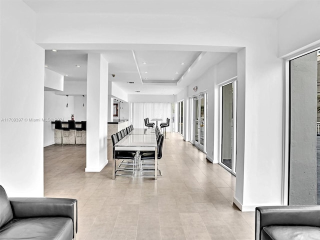 dining space featuring a tray ceiling and light tile patterned flooring