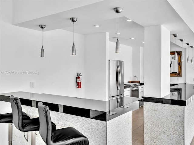 kitchen featuring kitchen peninsula, appliances with stainless steel finishes, a kitchen breakfast bar, pendant lighting, and light tile patterned flooring