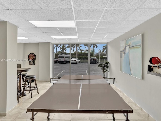 game room with a drop ceiling, light tile patterned floors, and a wall of windows