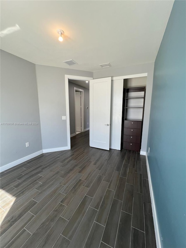 unfurnished bedroom featuring a closet and dark hardwood / wood-style flooring