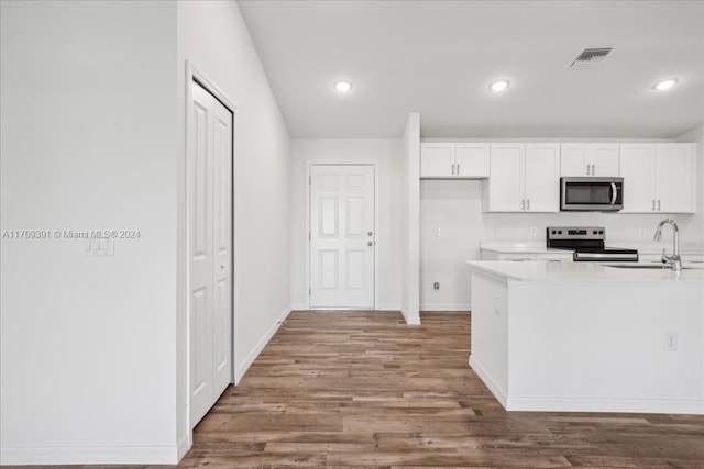 kitchen with hardwood / wood-style floors, appliances with stainless steel finishes, white cabinetry, and sink