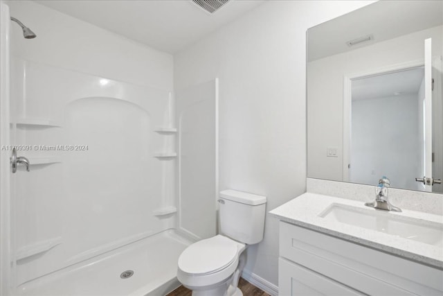 bathroom with walk in shower, vanity, and toilet