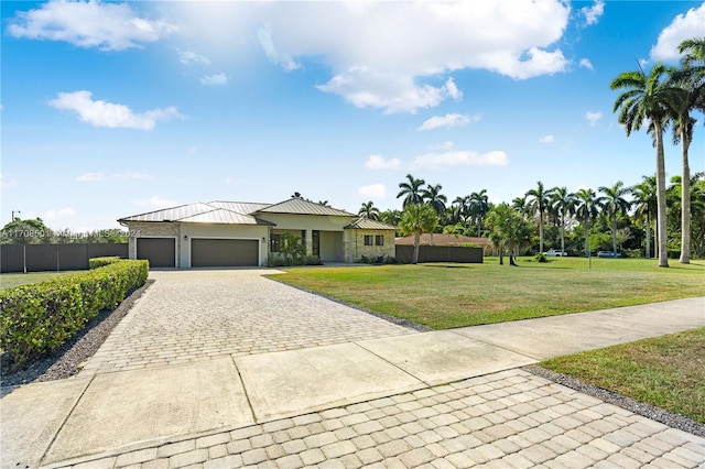 view of front facade featuring a front lawn, metal roof, an attached garage, stucco siding, and decorative driveway