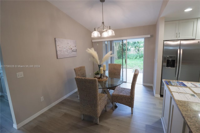 dining room featuring wood-type flooring, vaulted ceiling, and an inviting chandelier