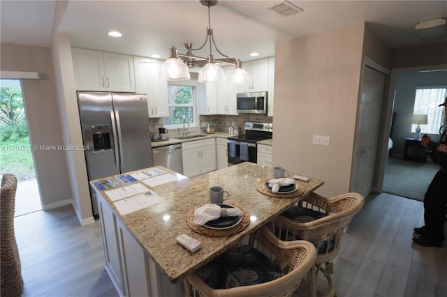 kitchen with sink, white cabinets, hanging light fixtures, and appliances with stainless steel finishes