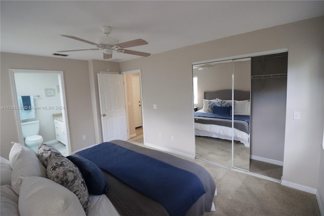 bedroom with a closet, ceiling fan, light colored carpet, and ensuite bathroom