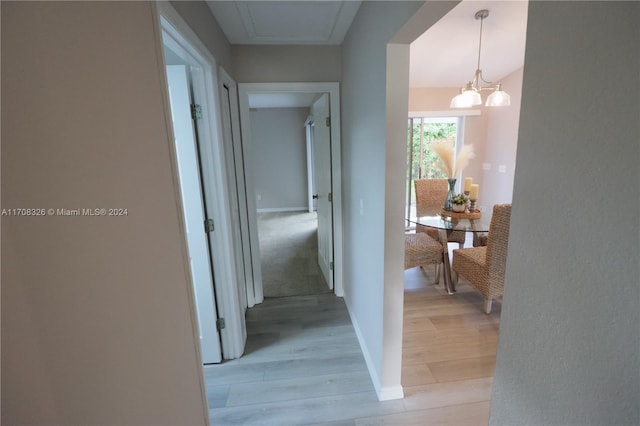 hallway with light hardwood / wood-style floors and a notable chandelier