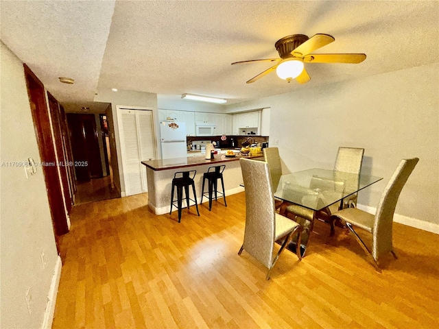 dining room featuring ceiling fan, a textured ceiling, and light hardwood / wood-style flooring