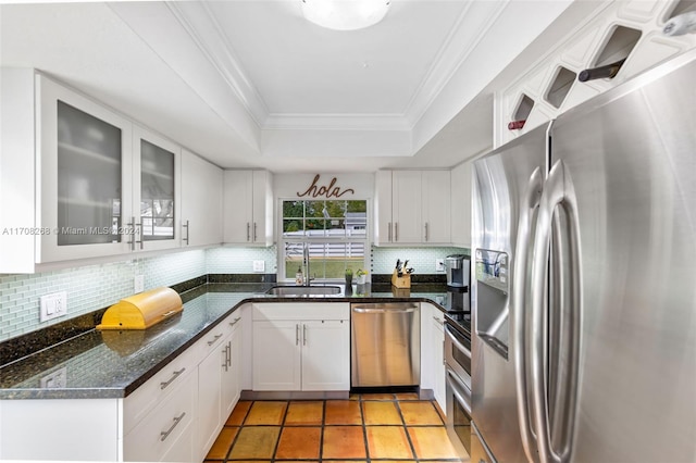 kitchen with appliances with stainless steel finishes, white cabinetry, a raised ceiling, and sink