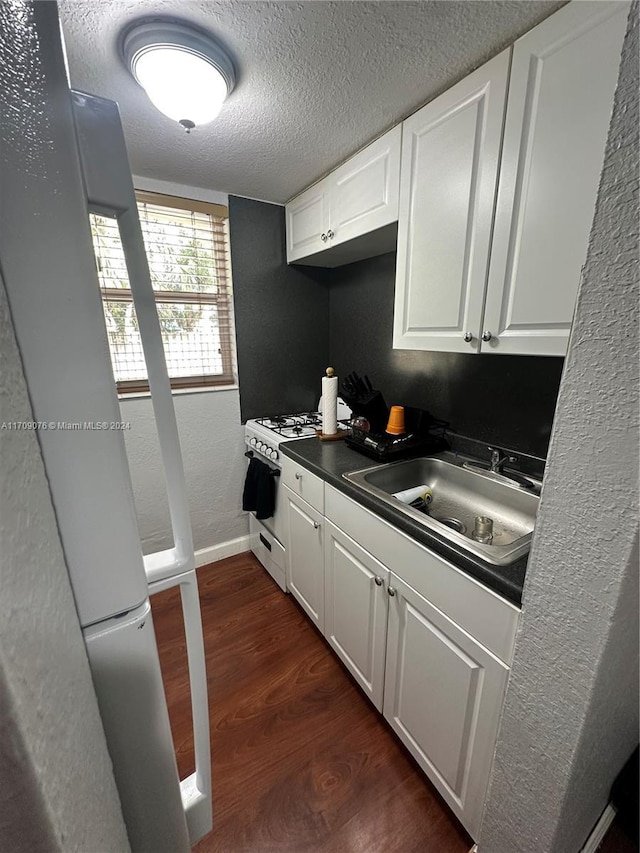 kitchen featuring gas range gas stove, a textured ceiling, sink, dark hardwood / wood-style floors, and white cabinetry