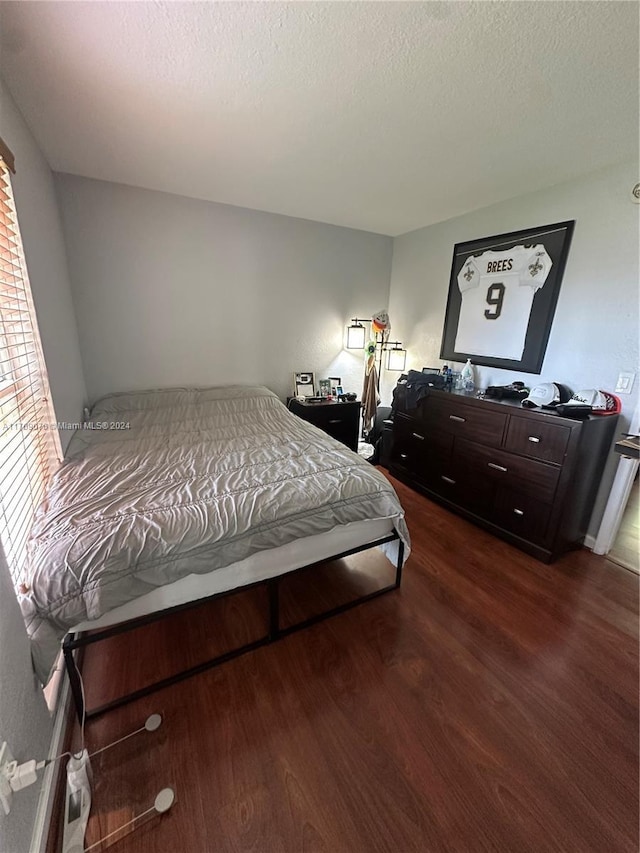 bedroom with dark hardwood / wood-style floors and a textured ceiling