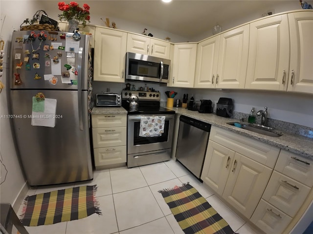 kitchen with light stone counters, sink, light tile patterned floors, and stainless steel appliances