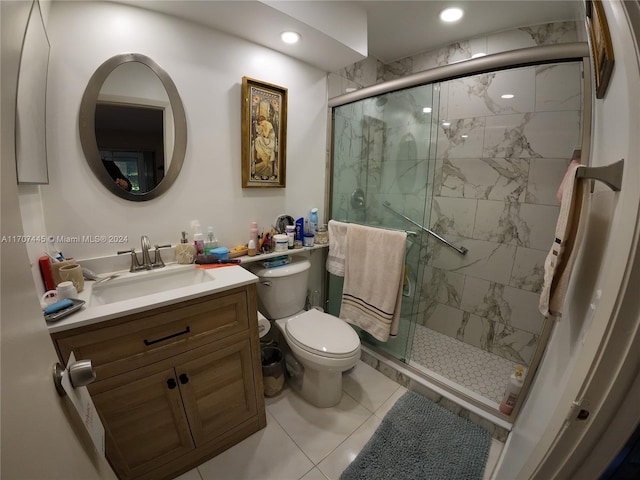 bathroom featuring tile patterned flooring, vanity, toilet, and a shower with door