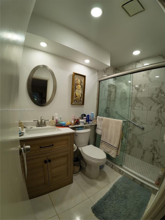 bathroom featuring toilet, vanity, tile patterned floors, and a shower with shower door