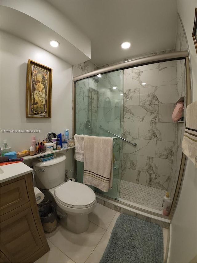 bathroom with tile patterned floors, a shower with door, vanity, and toilet