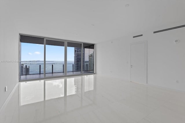 empty room featuring expansive windows, a water view, and light tile patterned floors